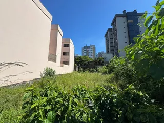 Vista externa mostrando vegetação densa em frente a um edifício residencial.