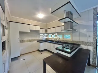Foto de uma cozinha interna com armários brancos e bancada escura.