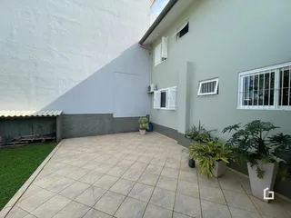 Vista da fachada de uma residência com pátio e jardim.