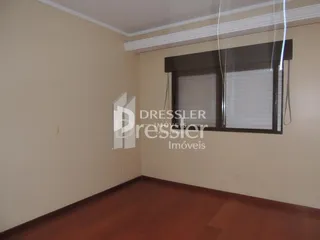 Interior de uma sala com piso de madeira e paredes claras.