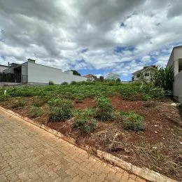Vista externa de um terreno com vegetação rasteira e pavimento.
