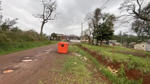 Vista externa de uma rua em uma área residencial em Lajeado, com vegetação e casas ao fundo.