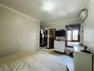 Quarto com cama e janela em ambiente claro.