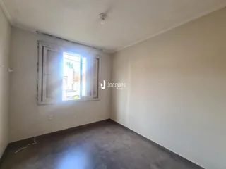 Foto de um cômodo interno com paredes brancas e piso cinza.