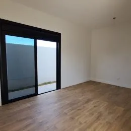 Sala de estar com piso de madeira e porta de vidro que dá para o exterior.