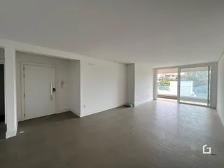 A foto mostra um espaço interno amplo com paredes brancas e piso de cerâmica.