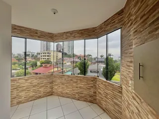 Sala de estar com grandes janelas que oferecem uma vista da paisagem urbana.