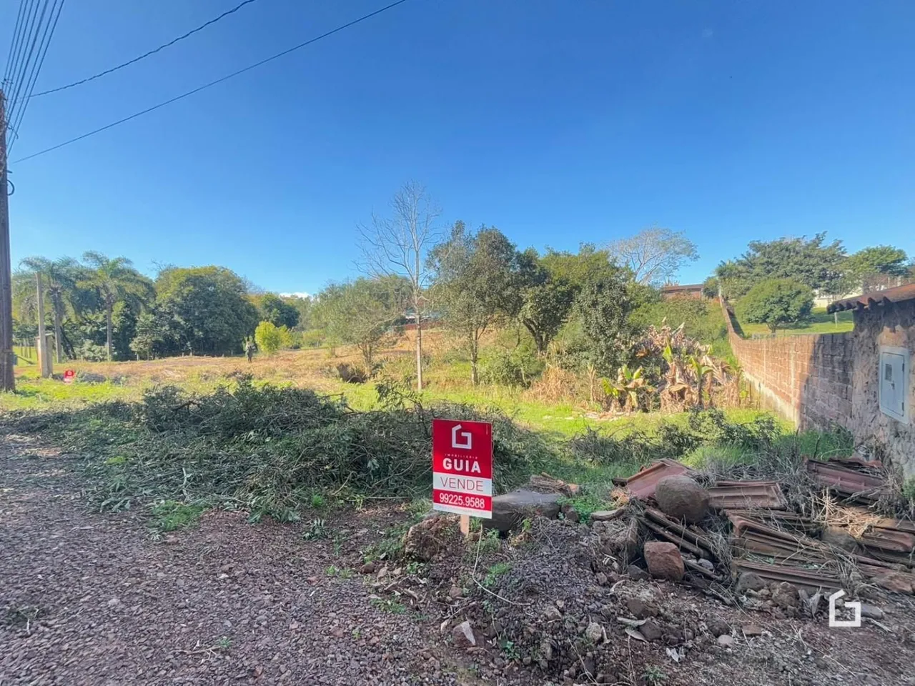 Vista externa de um terreno com vegetação e muro de contenção.