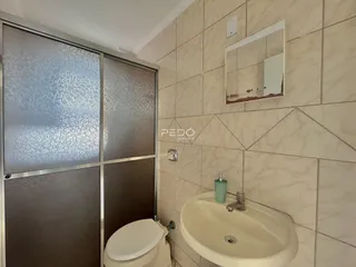 Foto de um banheiro com azulejos claros e louças sanitárias.