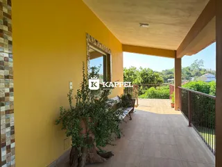 Varanda externa com piso de cerâmica e vista para a vegetação ao fundo.