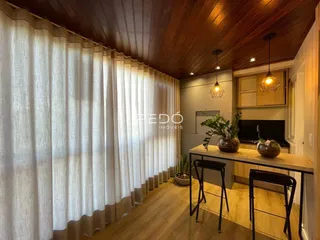 Ambiente interno com piso de madeira e cortinas brancas em um imóvel.
