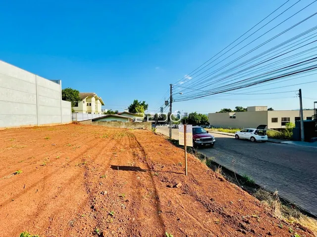 Terreno de terra avermelhada com muro e estrada no fundo.