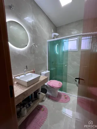 Foto de um banheiro com box de vidro e piso claro.