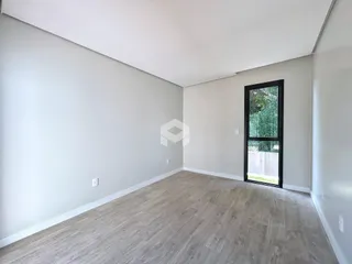 Ambiente interno de uma sala ampla com piso de madeira clara e paredes brancas.