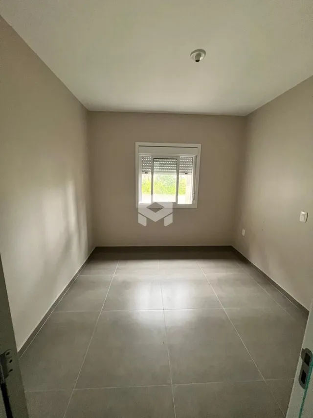 Vista interna de um cômodo com piso de cerâmica e parede clara.