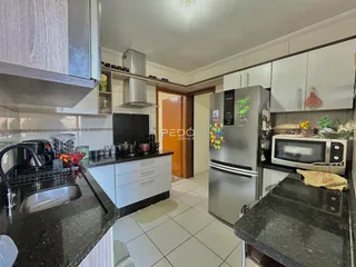 Cozinha moderna com armários brancos e bancadas escuras.