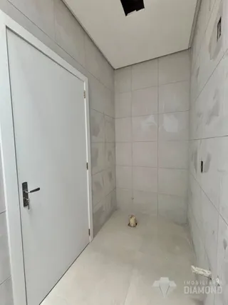 Hall de entrada com paredes brancas e piso claro.