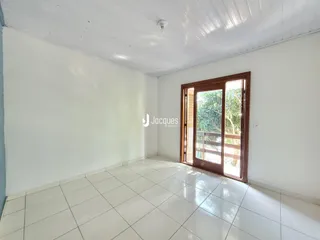 Sala de estar com piso de cerâmica branca e porta de madeira.