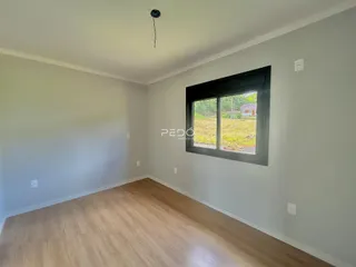 A sala apresenta paredes claras e piso de madeira.