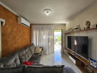 Sala de estar com sofá e cortinas brancas em um imóvel no Brasil.