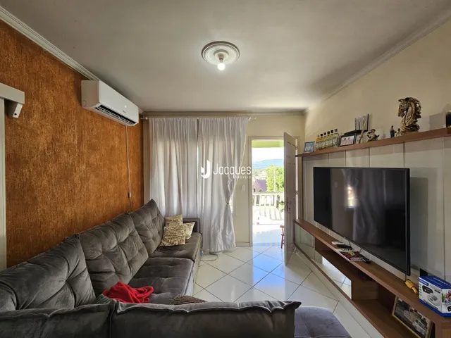 Sala de estar com sofá e cortinas brancas em um imóvel no Brasil.