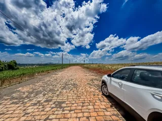 Vista de uma estrada de paralelepípedos atravessando campos verdes sob um céu azul.