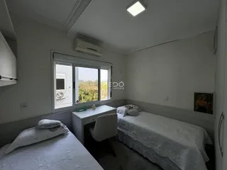 Quarto com duas camas de solteiro e janela com vista para a vegetação.