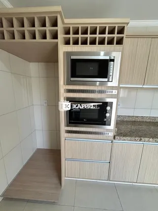 Uma estrutura de armários e prateleiras de madeira está instalada na parede da cozinha.