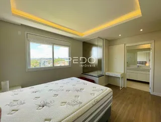 Quarto com cama e piso de madeira clara.