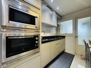Cozinha moderna com armários brancos e eletrodomésticos de aço inoxidável.