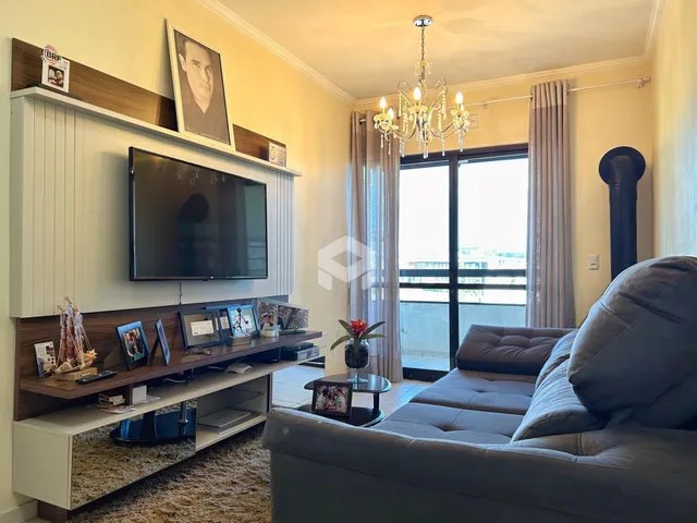 Sala de estar com sofá e televisão em um apartamento no Brasil.