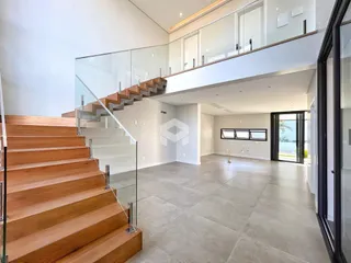Vista de uma escadaria com guarda-corpo de vidro em um apartamento.
