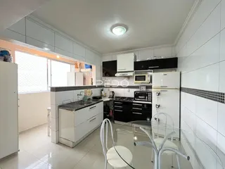 Foto de uma cozinha com armários brancos e eletrodomésticos pretos.