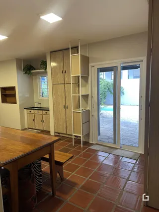 Sala de jantar com piso de tijolos vermelhos e porta de vidro dando acesso ao exterior.