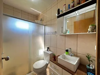 Um banheiro com revestimento de cerâmica bege e louças brancas.