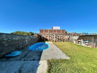 Vista externa de uma propriedade com piscina e área gramada.