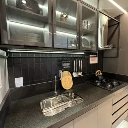 Vista da bancada da cozinha com pia e revestimento escuro.