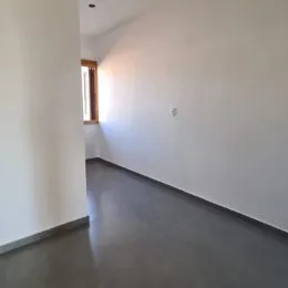 Corredor interno com paredes brancas e piso cinza.