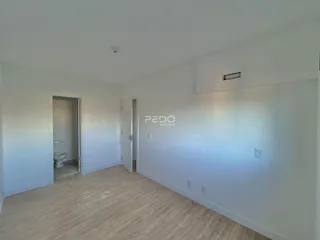 Ambiente interno com piso de madeira clara e paredes brancas.