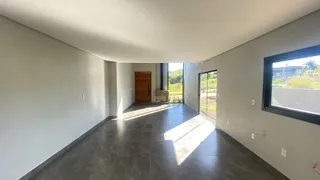 Corredor interno com piso escuro e paredes brancas, com acesso a uma área externa.