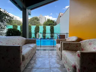 Vista de uma área externa com sofás voltados para uma piscina no Brasil.