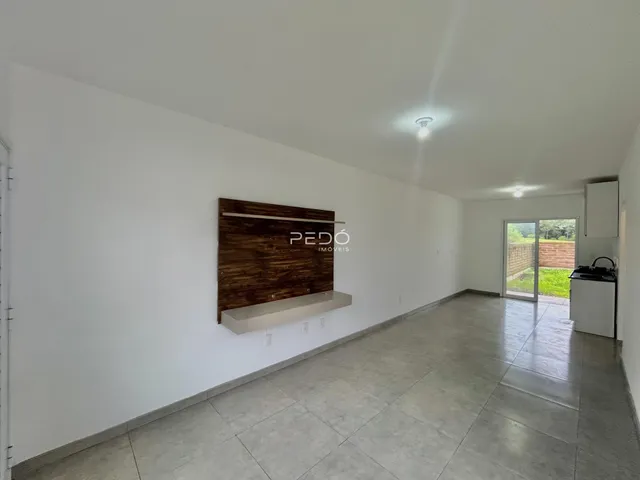 Interior de uma sala ampla com piso de cerâmica e parede de destaque de madeira.