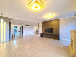 Sala de estar ampla com piso de madeira clara e teto alto.
