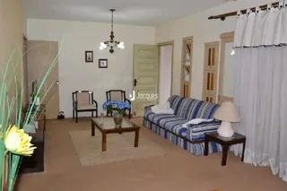 Sala de estar interna com sofá e cortinas brancas.