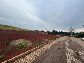 Vista da propriedade com terreno de terra vermelha e estrada de acesso.