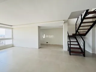 Sala de estar ampla com piso claro e parede branca.