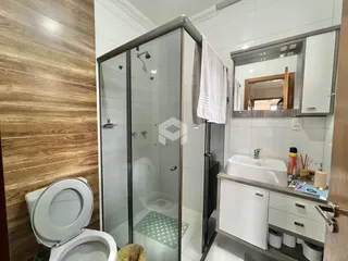 Banheiro com box de vidro e louças brancas em um imóvel.