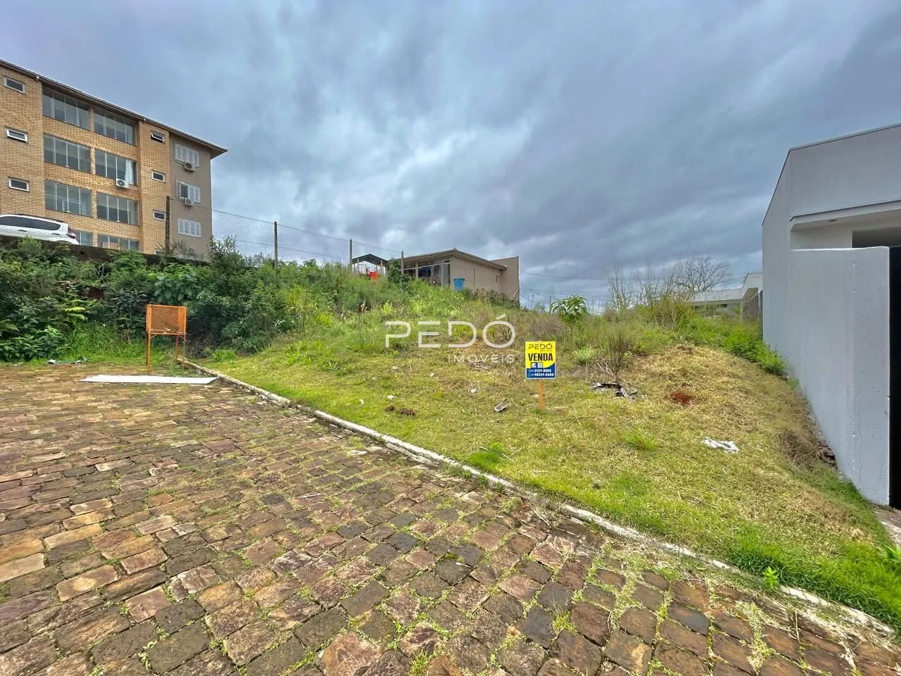 Vista externa de um terreno com pavimentação e vegetação.