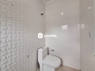 Banheiro com paredes brancas revestidas e vaso sanitário branco.
