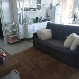 Foto interna de uma sala com sofá escuro e armários brancos.